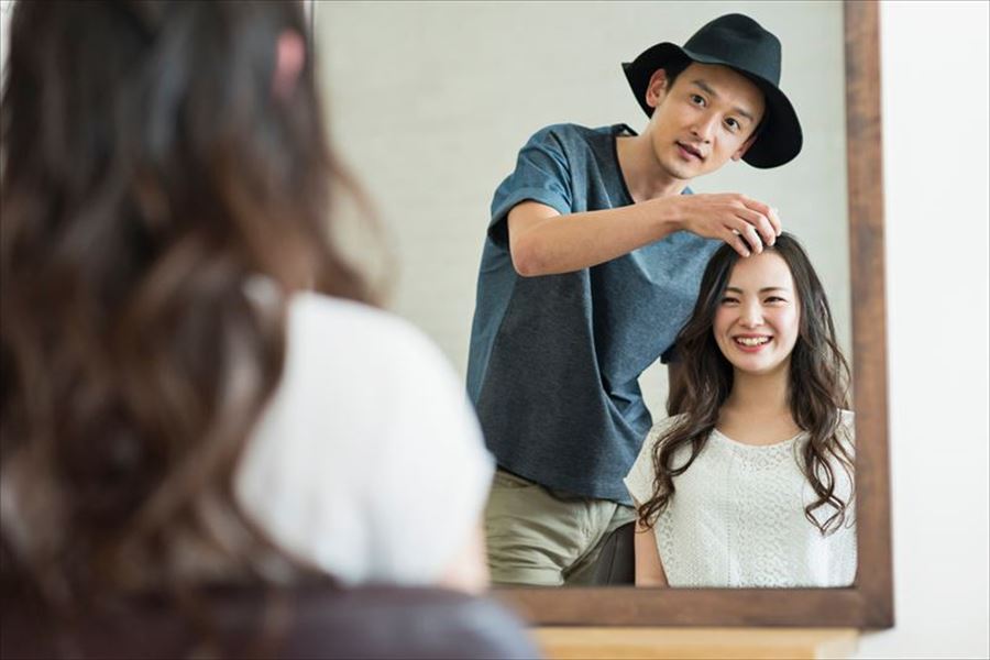 女性客のヘアスタイルを整える男性美容師